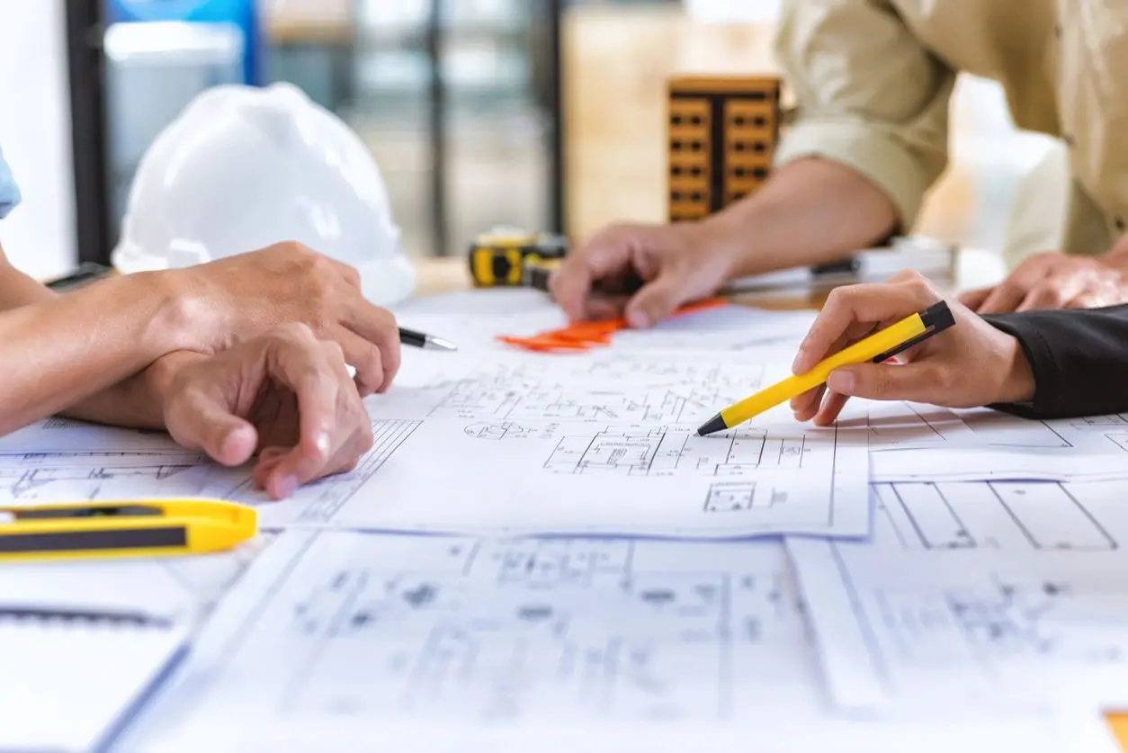 A group of people sitting at a table with construction plans.